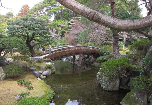 An arched wooden bridge over the pond in a garden of the Kyoto Imperial Palace