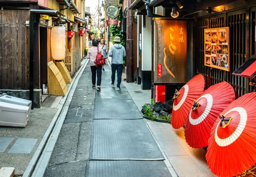 Red paper parasols outside a restaurant along the narrow stone lane of Pontocho, Kyoto