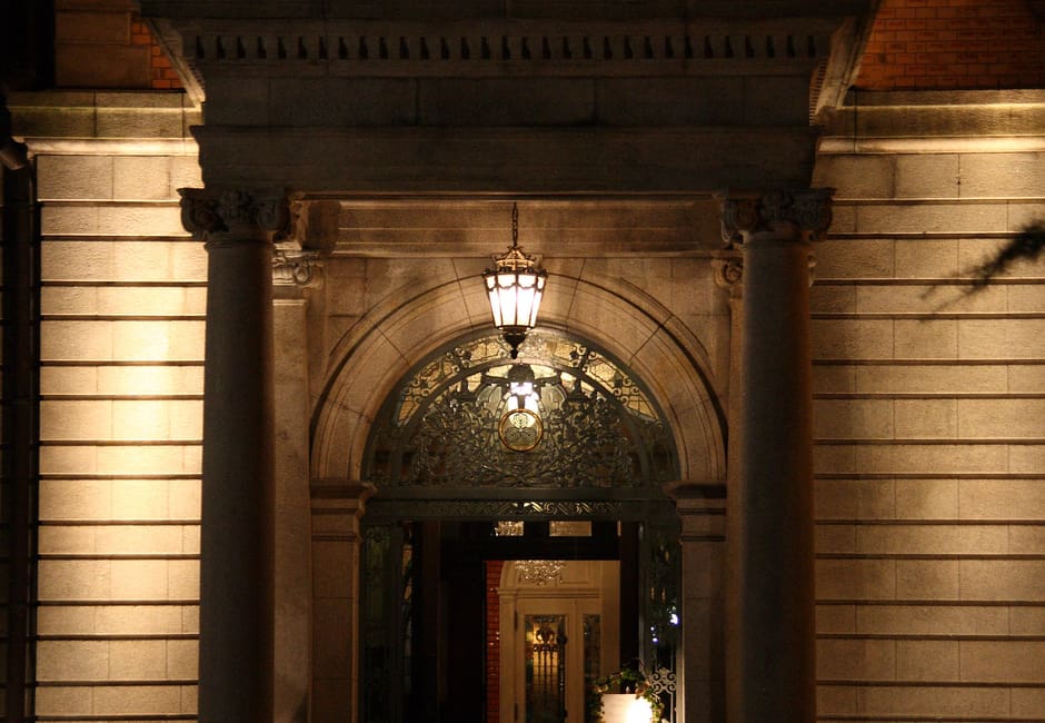 The lit stone portico and arched front door of Chourakukan, the 1909 Western-style mansion by Maruyama Park, at night