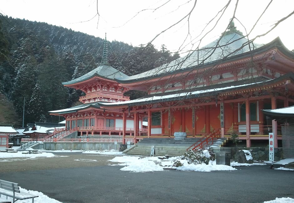 Vermilion halls and a two-storey pagoda of Enryaku-ji on Mount Hiei, with snow on the ground