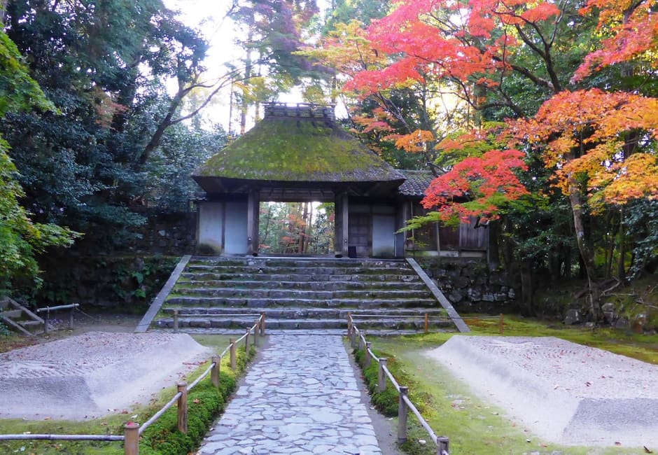The moss-roofed thatched gate of Honen-in between sand mounds and autumn maples