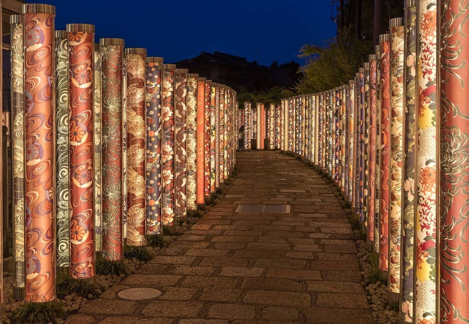 The lit kimono fabric pillars of the Kimono Forest at Arashiyama Station at night, Kyoto