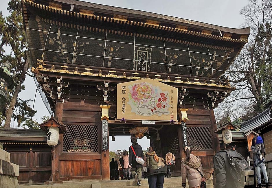 The carved Sanmon gate of Kitano Tenmangu hung with a large ema plaque