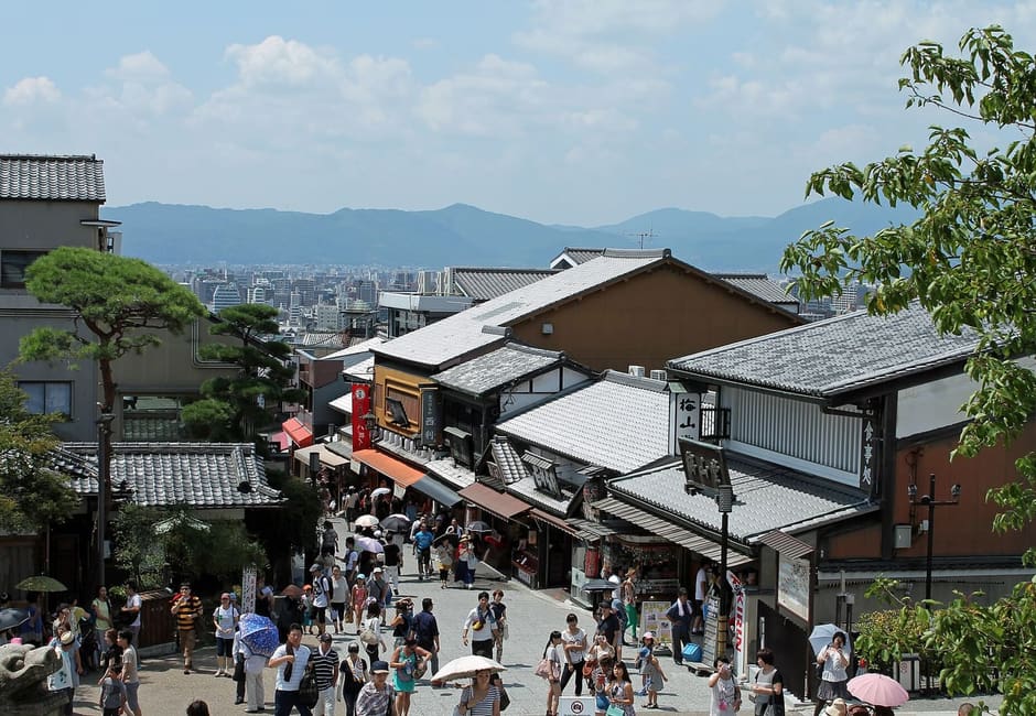 Looking down Kiyomizu-zaka over shop roofs and crowds towards the city of Kyoto