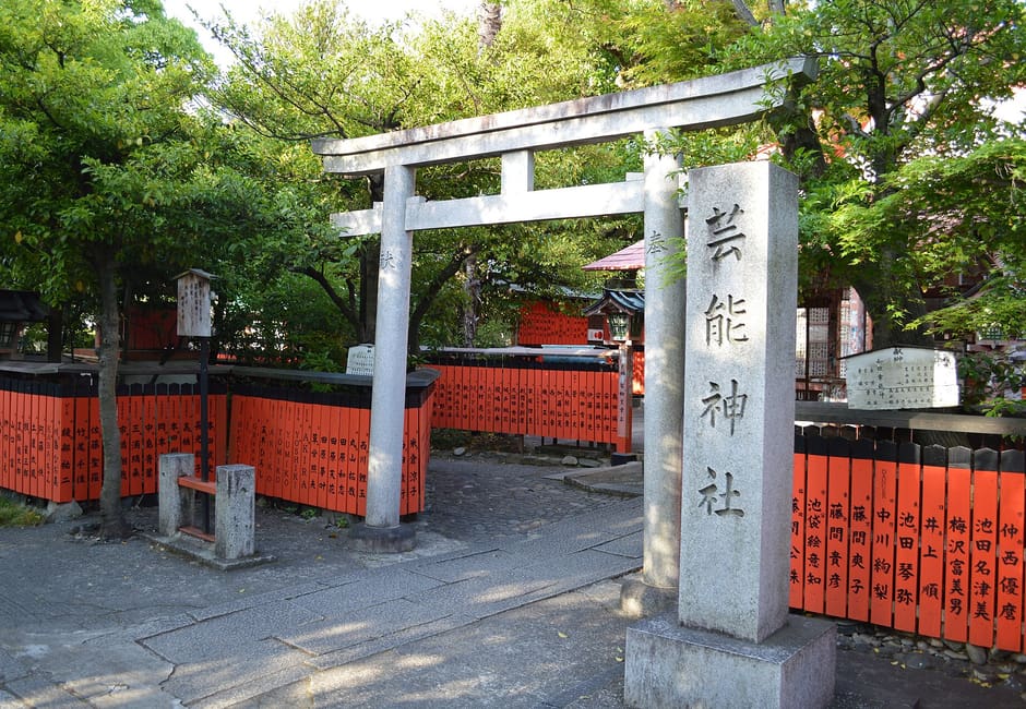 The stone torii and name pillar of the Geino Shrine at Kurumazaki Shrine, ringed by red boards with performers' names