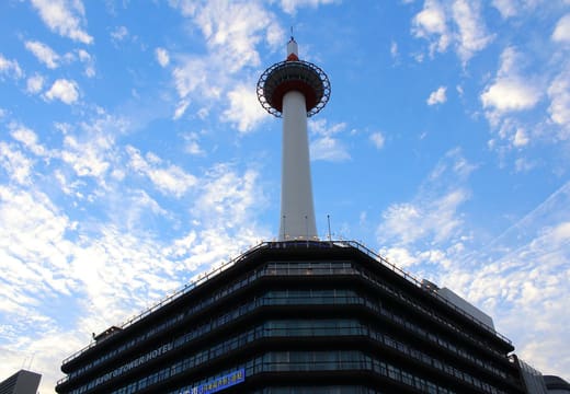 Kyoto Tower rising above its base building against a blue sky