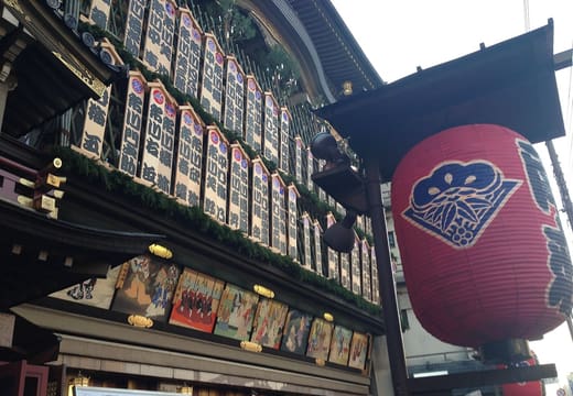 The facade of the Minamiza kabuki theatre hung with actor signboards and a red lantern