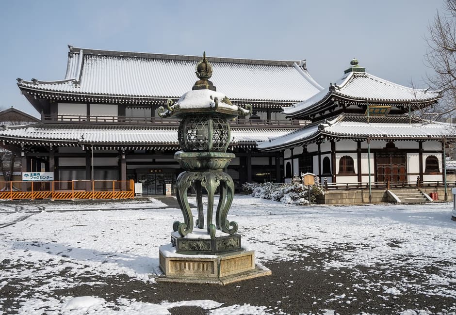 The great wooden halls of Nishi Hongan-ji after a snowfall, with a bronze lantern
