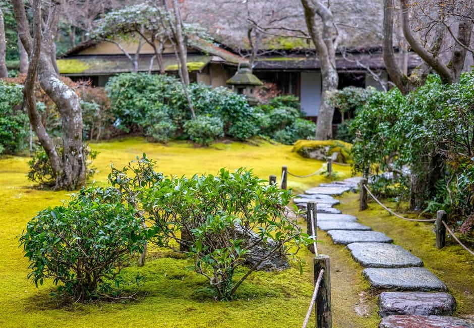 A moss garden and stone path in front of a villa building at Okochi Sanso