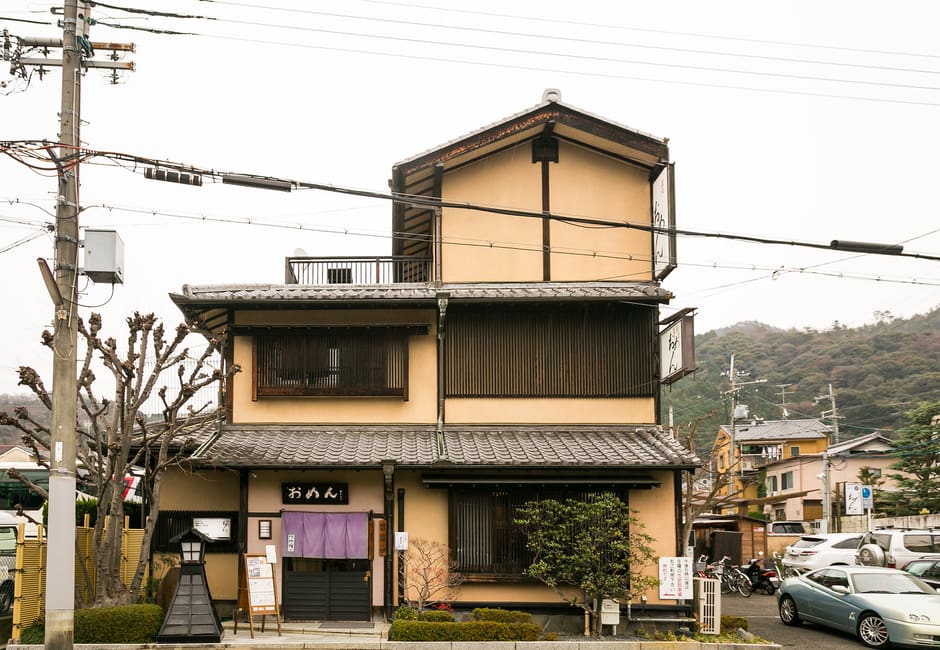 Omen Ginkakuji's wooden shop with its おめん sign and purple noren, the Higashiyama hills behind