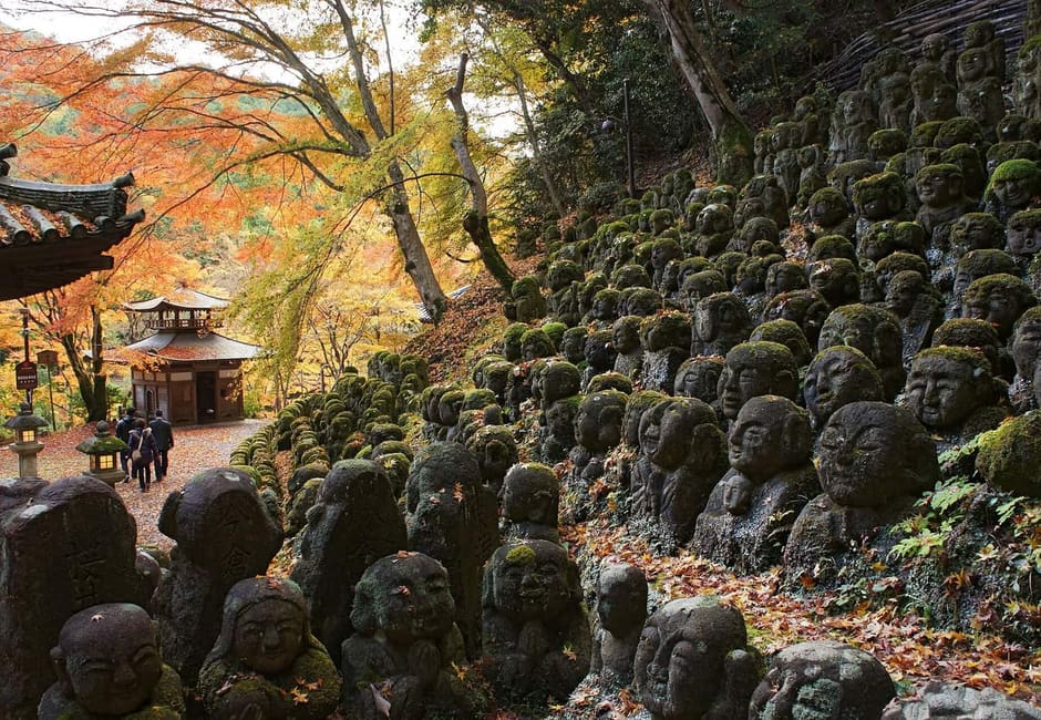 Moss covered rakan statues on the slope of Otagi Nenbutsu-ji among autumn maples, Kyoto