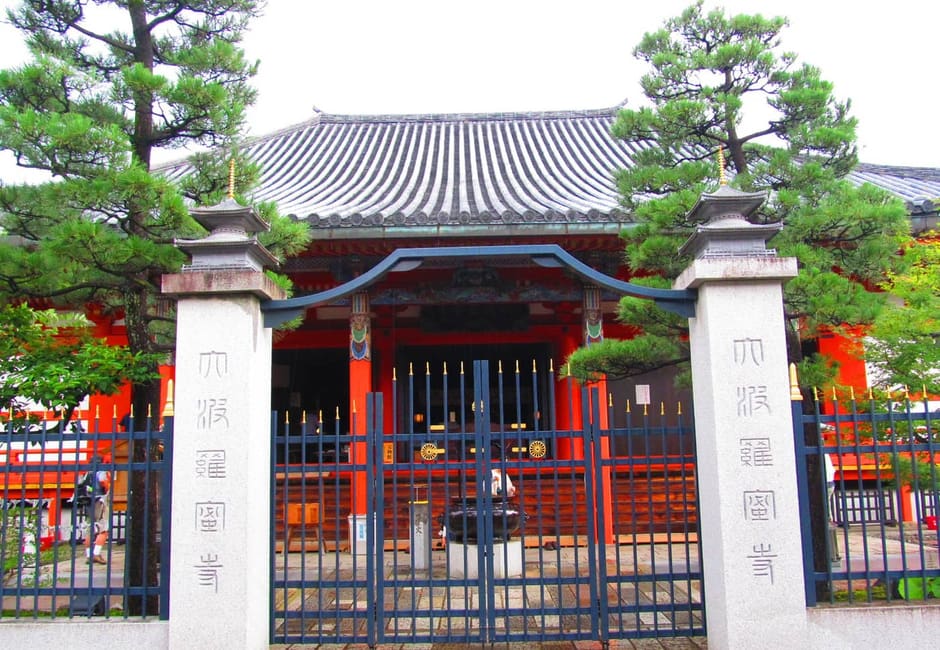 The vermilion main hall of Rokuharamitsu-ji behind its stone gateposts