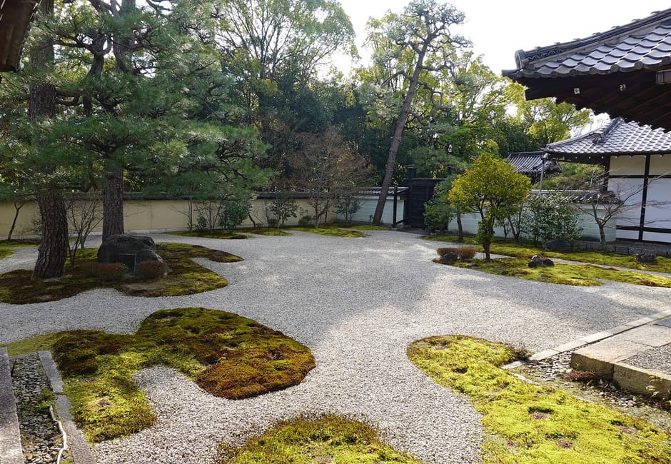 The Genji garden at Rozan-ji, white gravel with curving islands of moss and pine trees behind