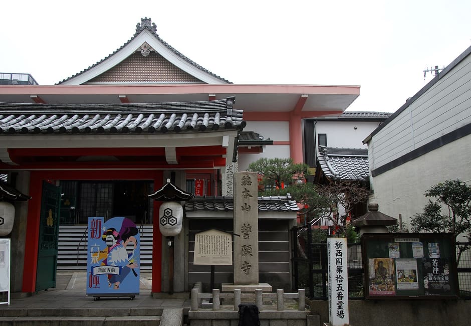 The front of Seigan-ji on Shinkyogoku, with red pillars, white paper lanterns and a stone marker before the hall