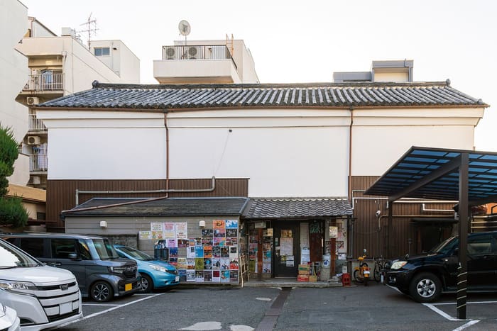 The white-walled exterior of the Takutaku live house in Kyoto with posters by the entrance