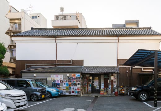 The white-walled exterior of the Takutaku live house in Kyoto with posters by the entrance